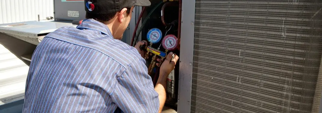 HVAC technician servicing a condenser unit in Egelston